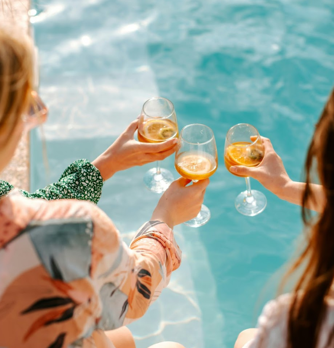a group of people holding wine glasses by a pool