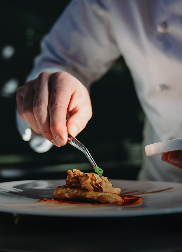 a person holding tweezers over food