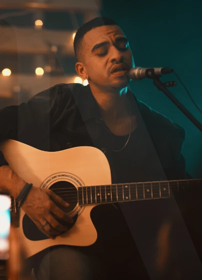 a man playing guitar and singing into a microphone