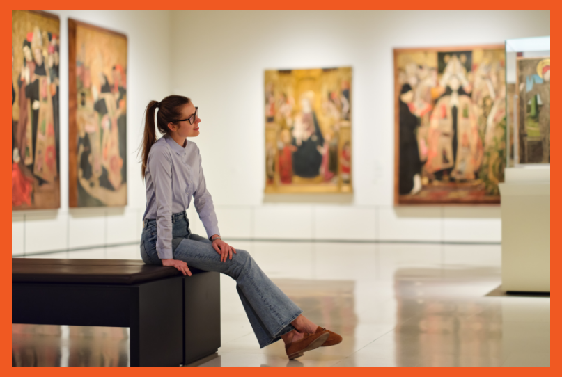a woman sitting on a bench in a museum