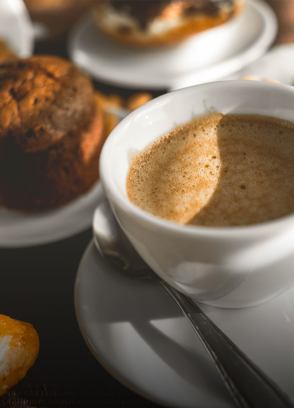 a cup of coffee with a spoon and a muffin