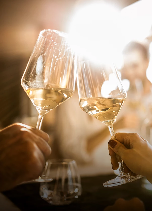 a pair of hands holding wine glasses