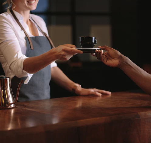 a person handing a cup of coffee to a woman