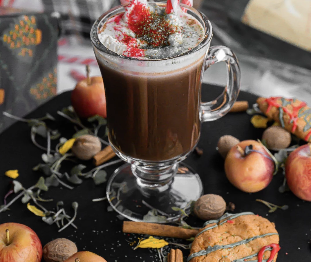 a glass of hot chocolate with candy canes and cookies