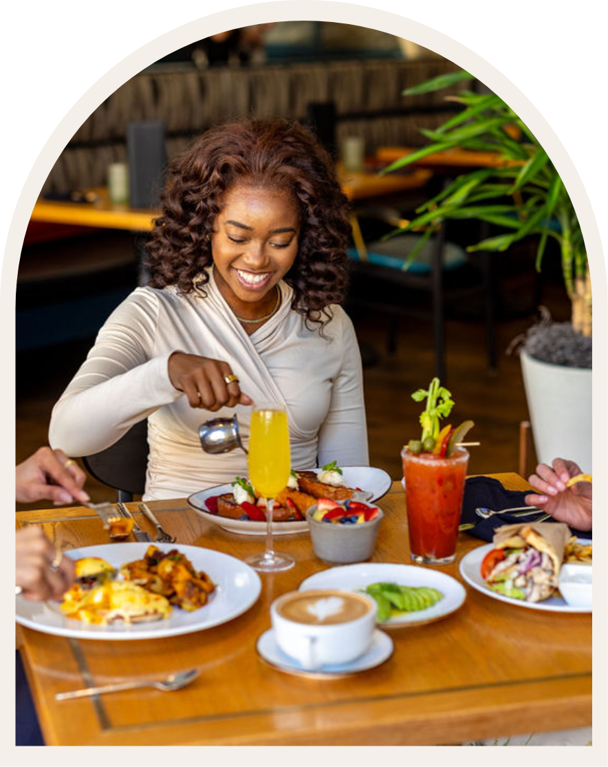 a woman pouring orange juice into a plate of food