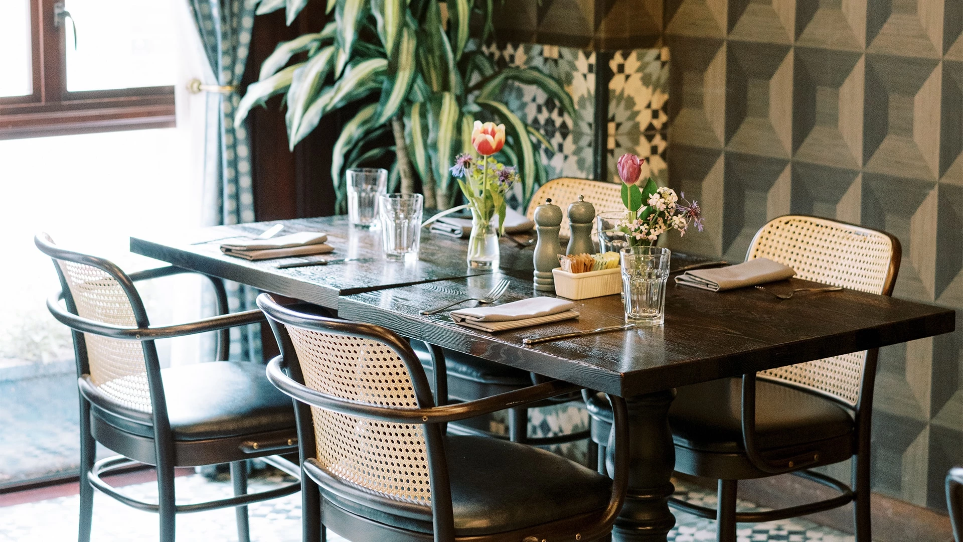 a dining table set for four people with flowers in vases