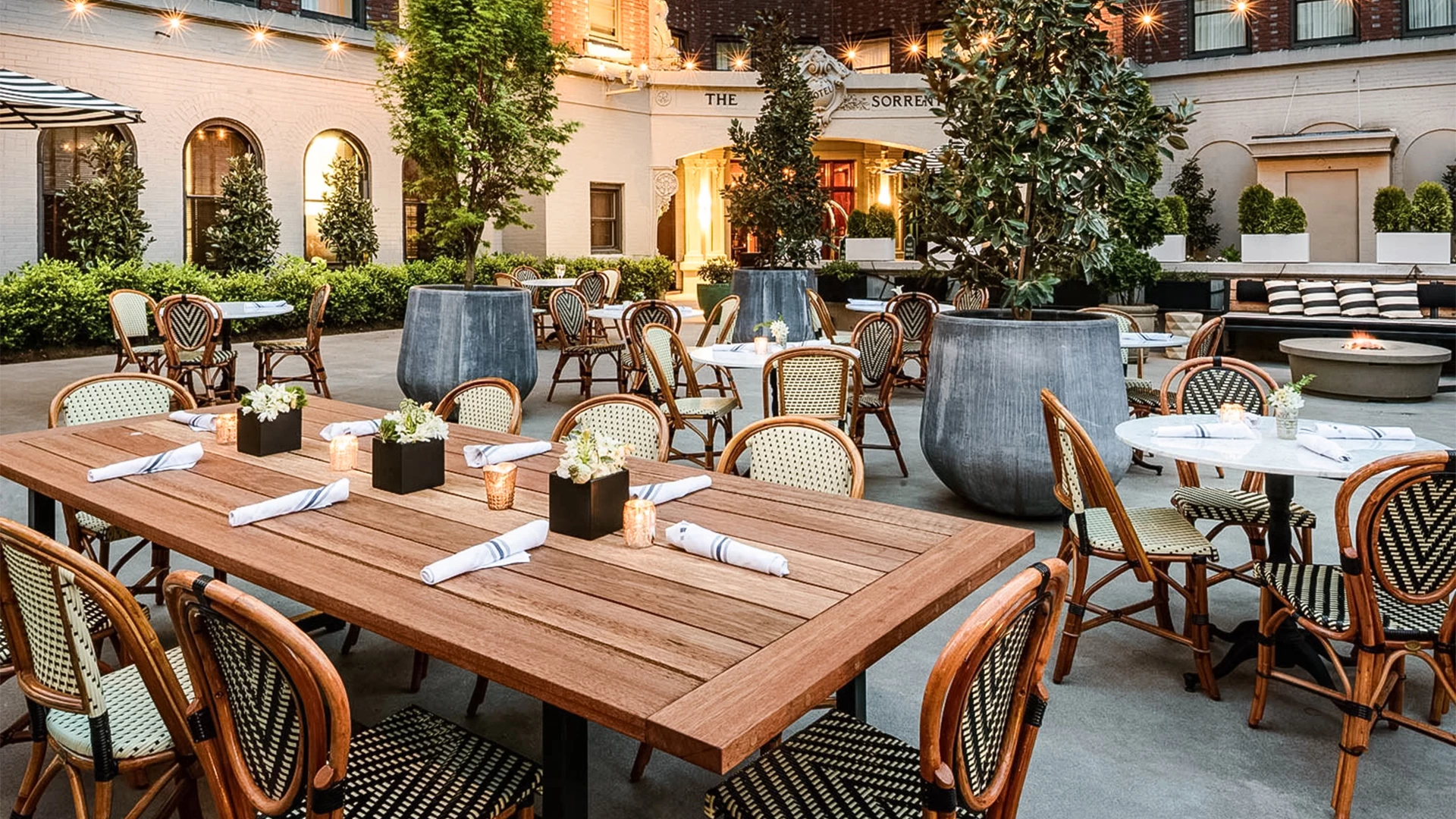 A cozy outdoor dining area with tables, chairs, and a fire pit.