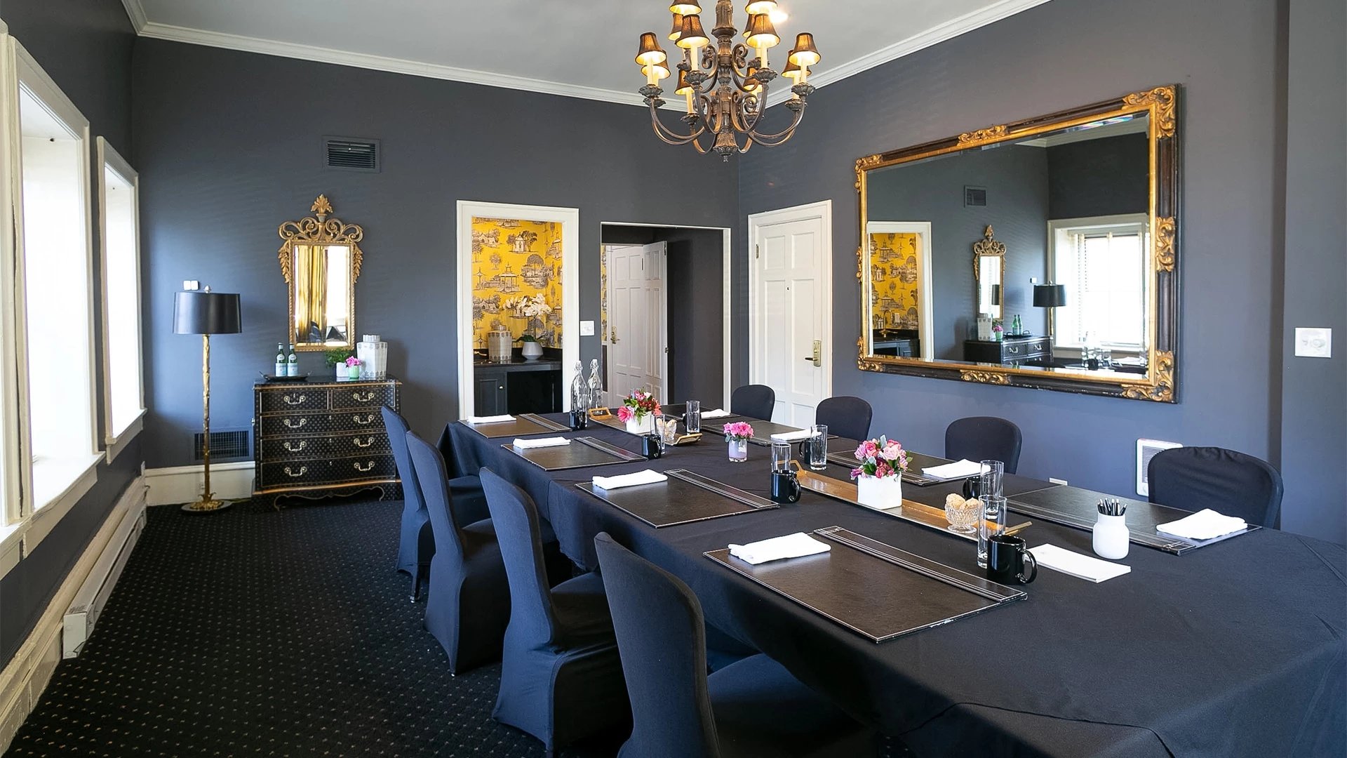 A large meeting room with a long table, chairs, and a mirror on the wall