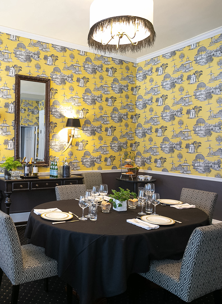 a dining room with a black tablecloth and yellow wallpaper