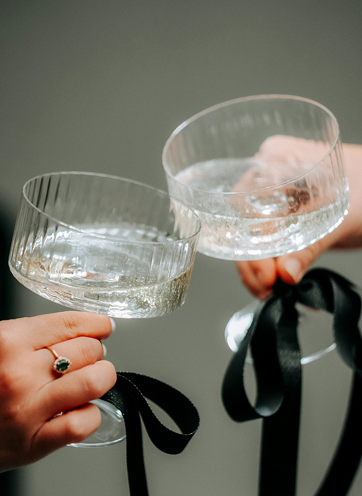 a pair of hands holding glasses with black ribbons