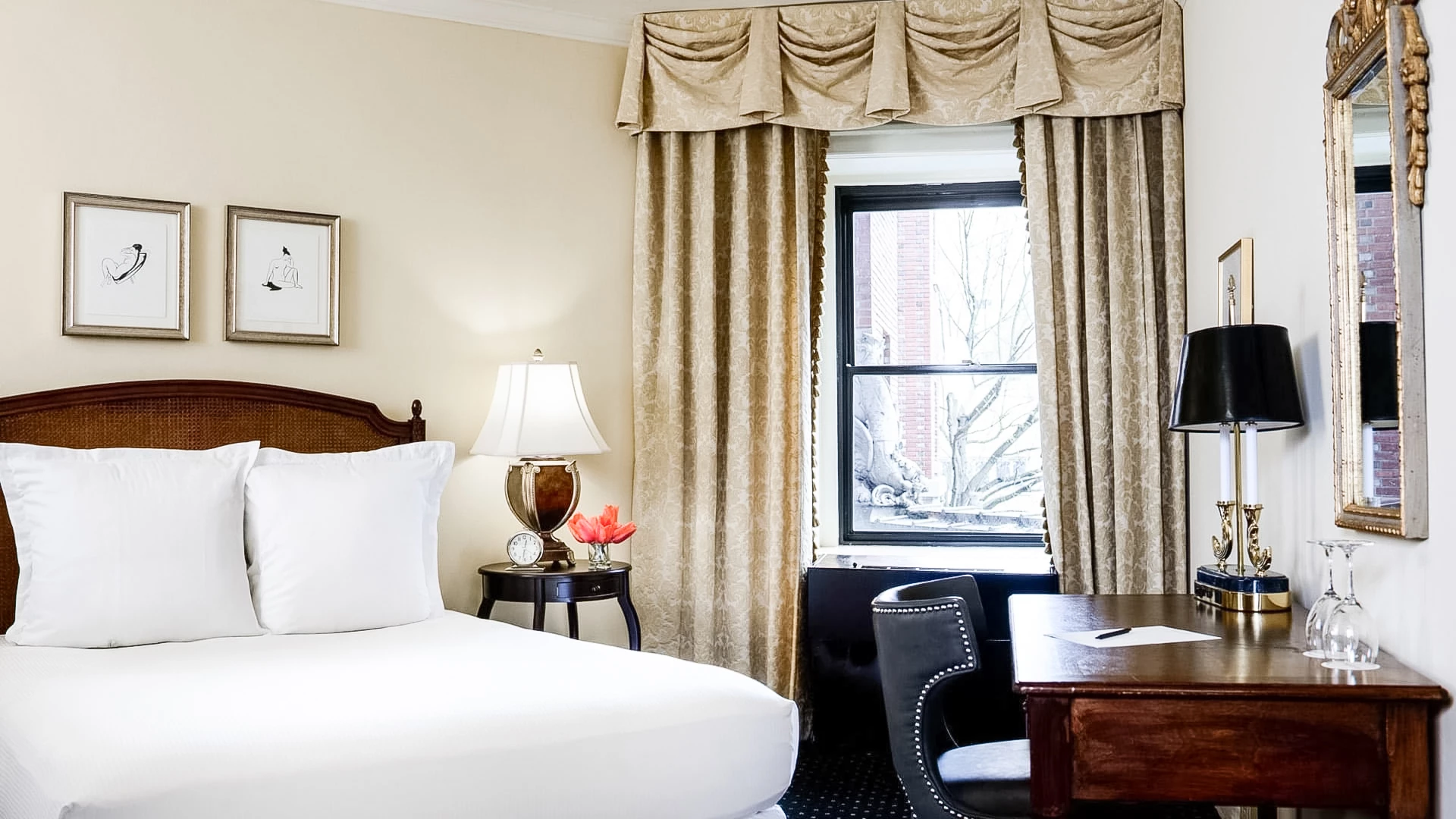 A hotel room with a bed, desk, and window