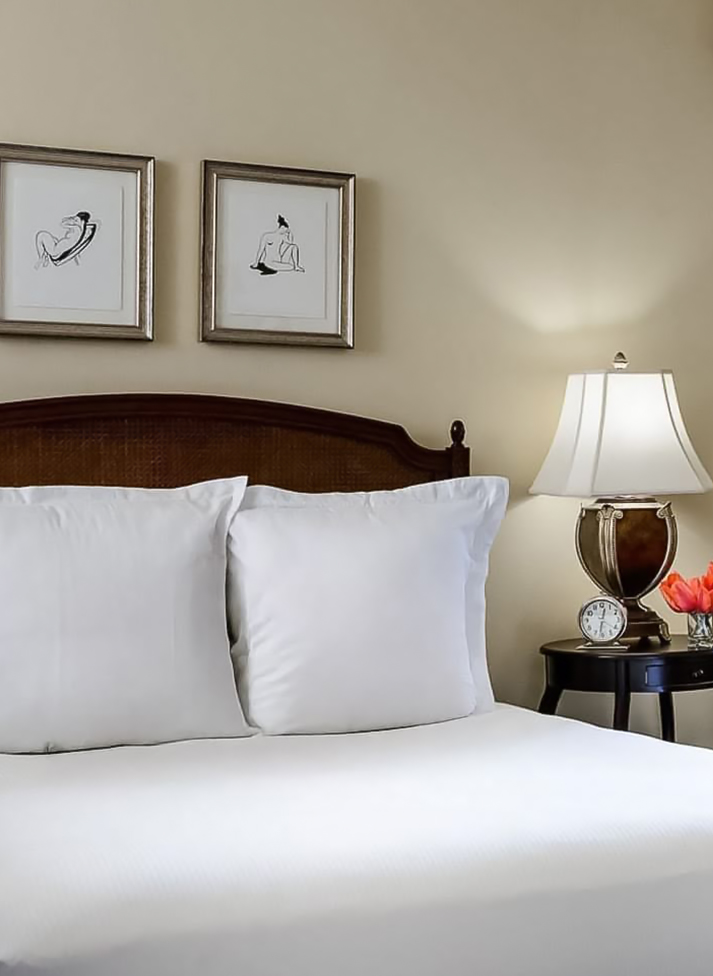 a bed with a lamp and a flower on a table