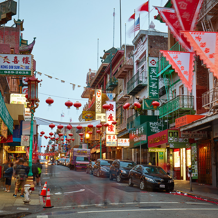 a street with cars and flags with Chinatown in the background
