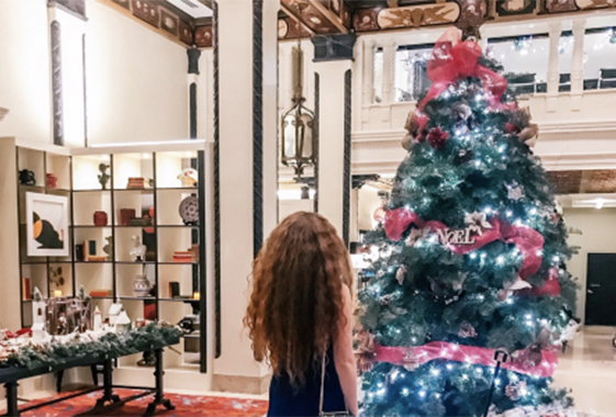 a girl standing in front of a christmas tree