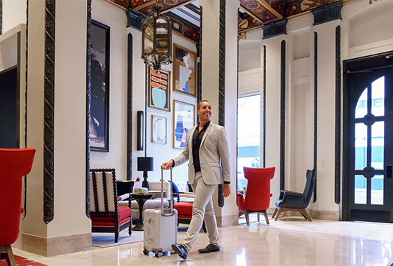 a man in a suit walking with a luggage in a hotel lobby