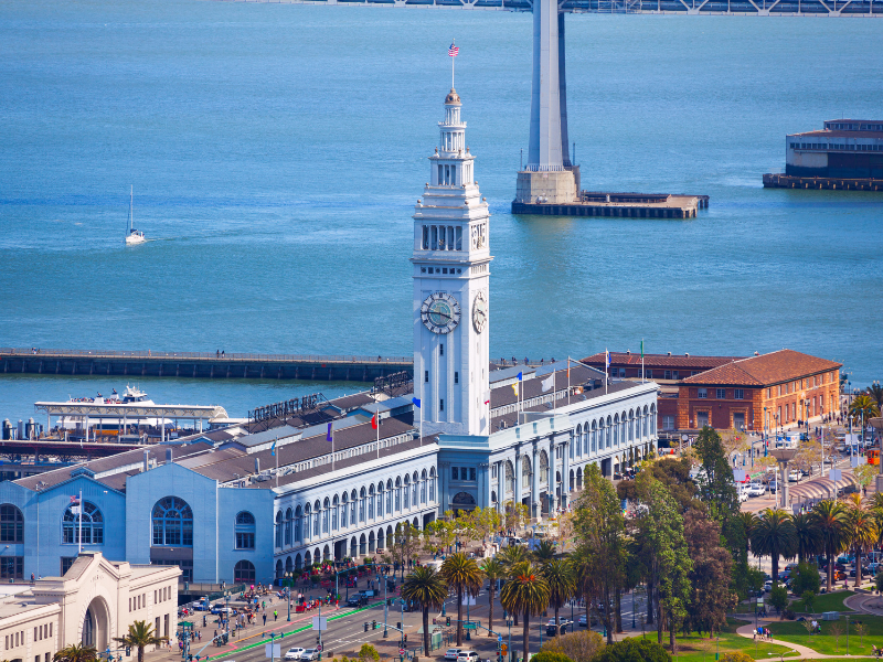 The historic Ferry Building in San Francisco, with its iconic clock tower overlooking the bay and bustling Embarcadero waterfront below