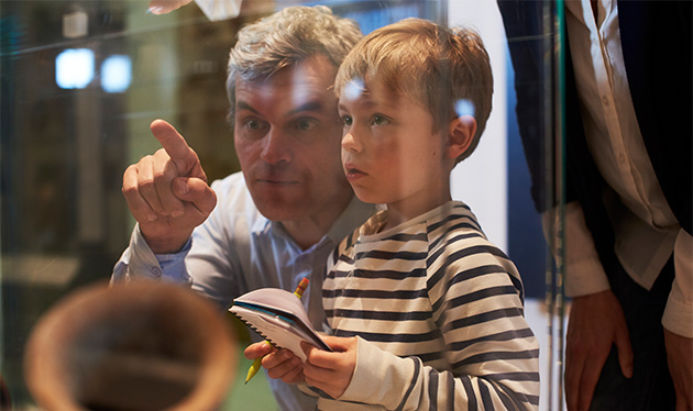 Adult pointing out an exhibit to a curious child taking notes at the California Academy of Sciences in San Francisco, a hands-on science museum with interactive learning for all ages