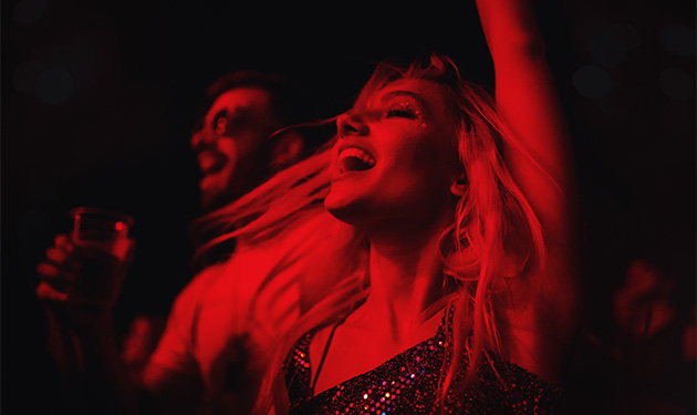Guests enjoying a live performance at Club Fugazi in San Francisco, with vibrant red lighting and energetic expressions capturing the excitement of the show