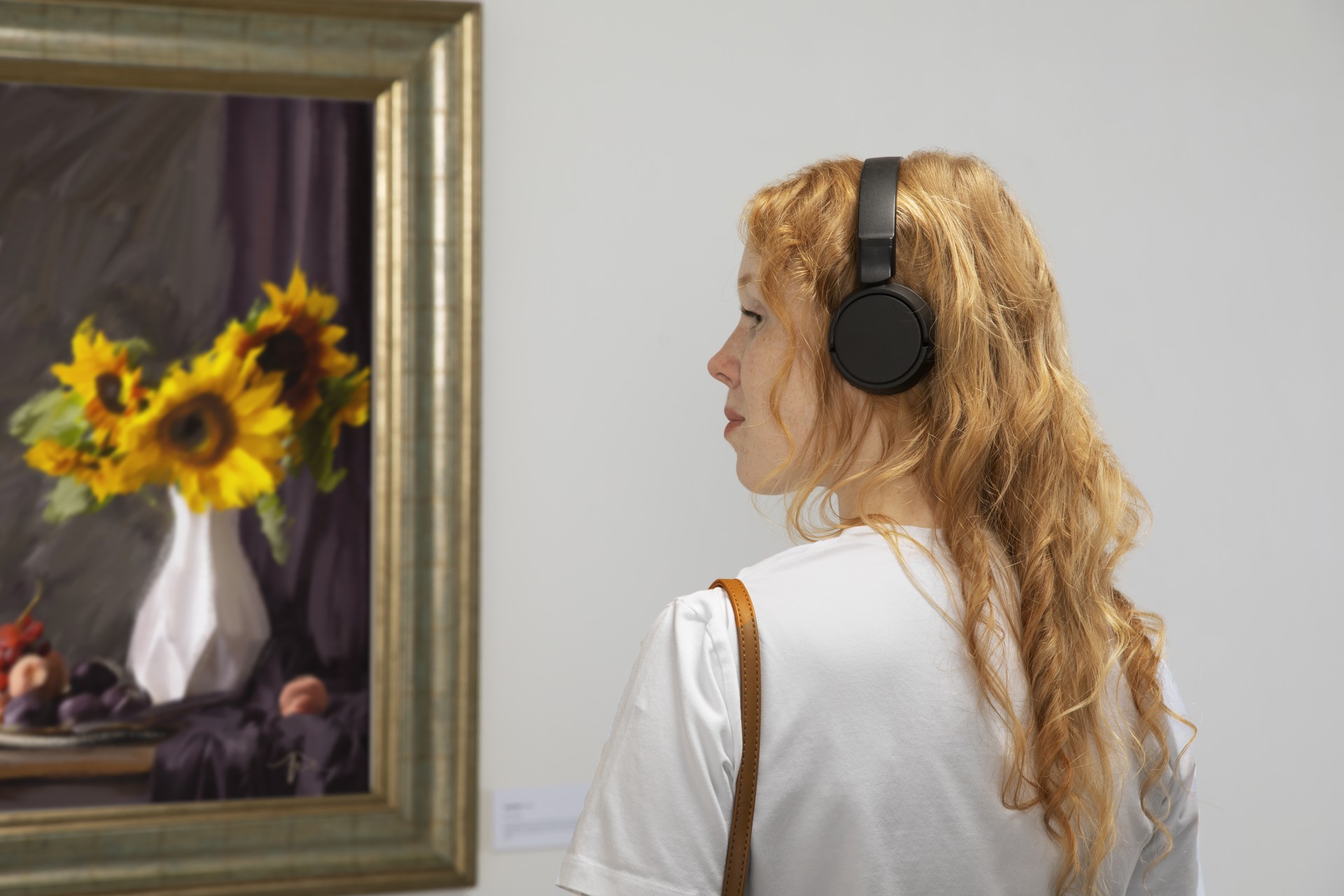 Visitor with headphones viewing a sunflower still life painting at the de Young Museum in San Francisco