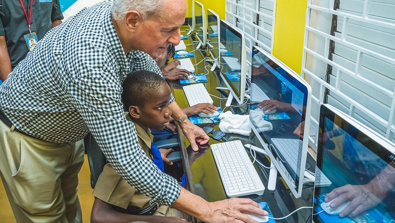 a man and boy sitting at a desk with computers