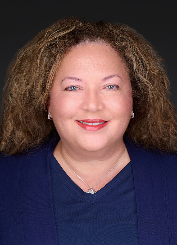 a woman with curly hair wearing a blue shirt and a necklace
