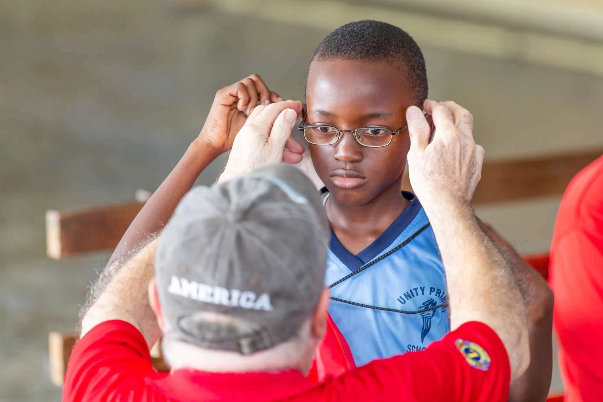 a man helping a boy to put on glasses