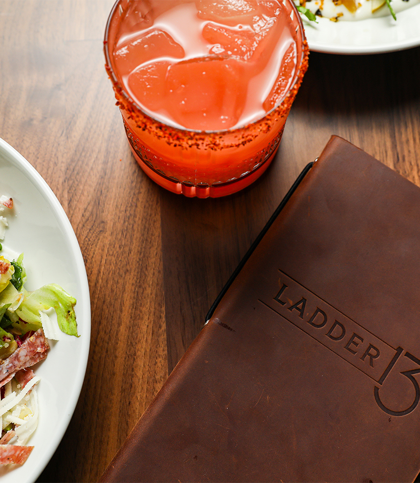 a plate of salad and a glass of liquid next to a menu