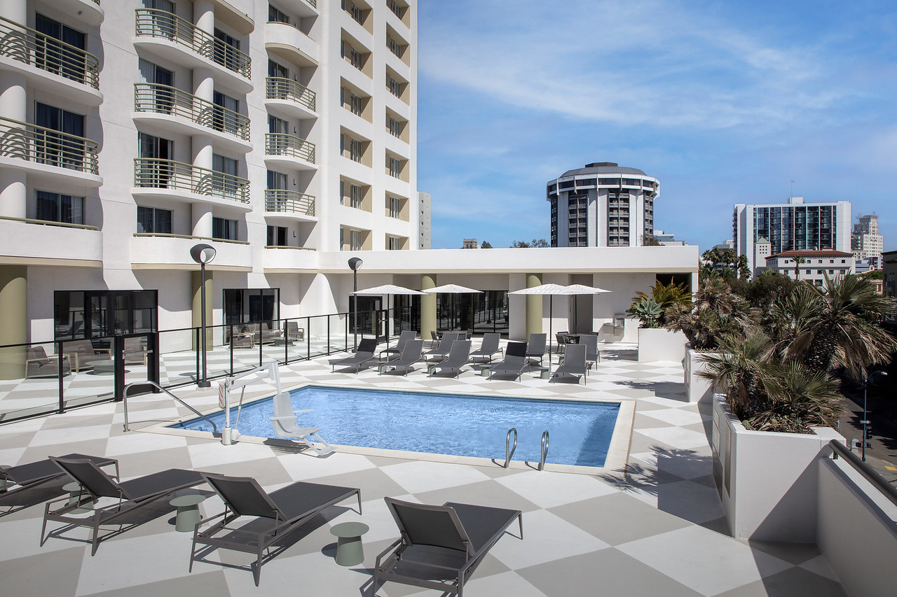a pool with lounge chairs and umbrellas in front of a building