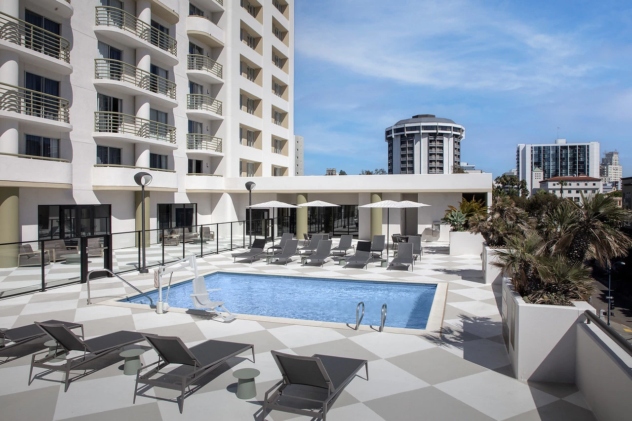 a pool with lounge chairs and umbrellas in front of a building
