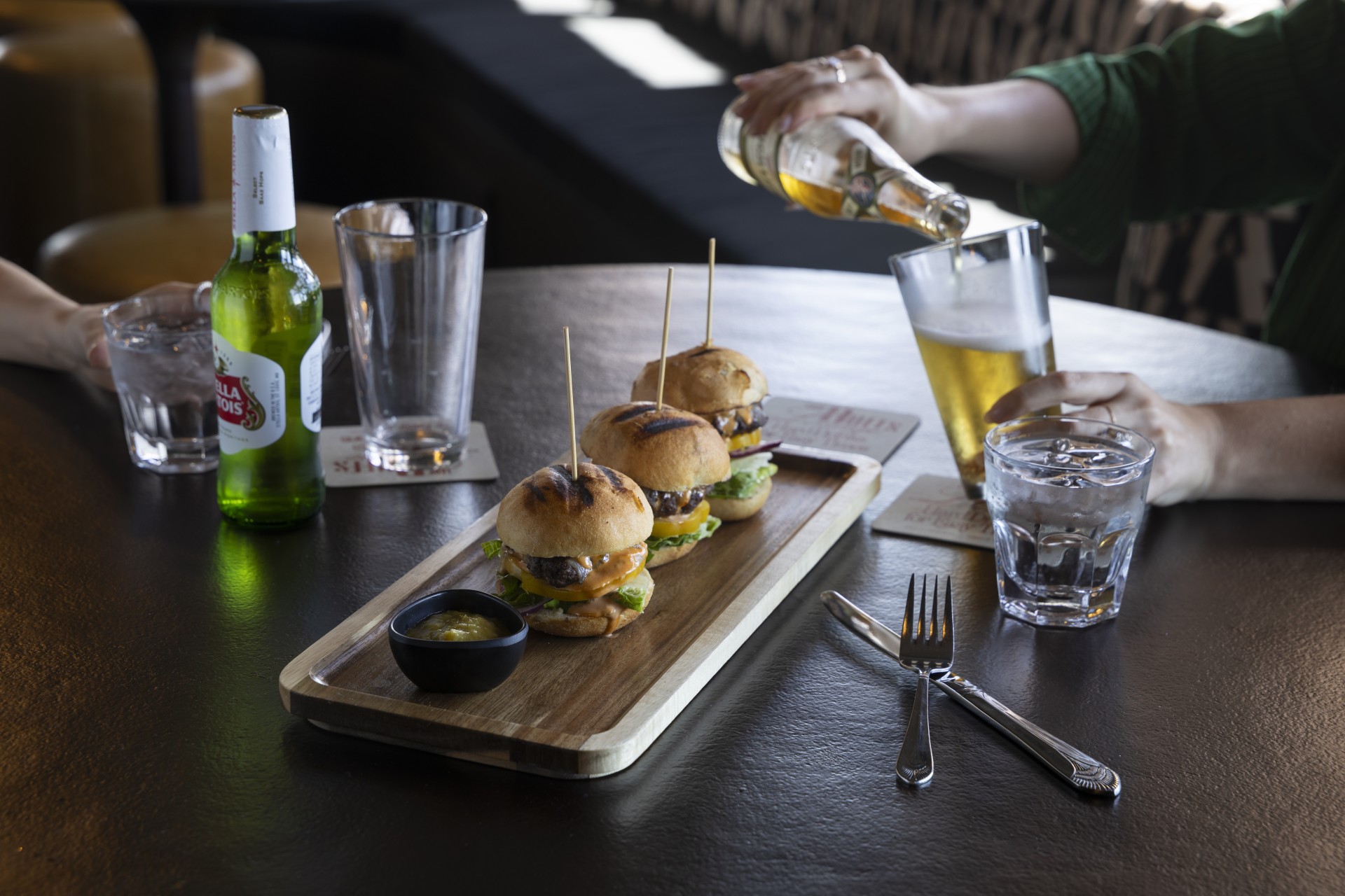 a tray of burgers on a table with a person pouring beer