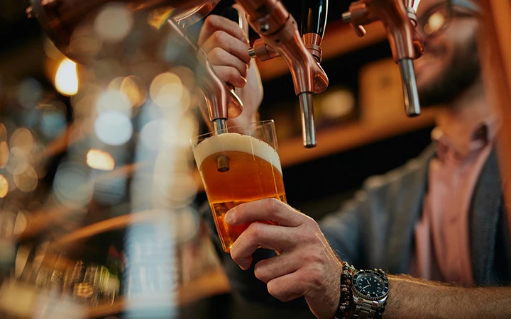 a person pouring a beer from a tap