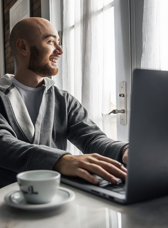 a man smiling at a laptop