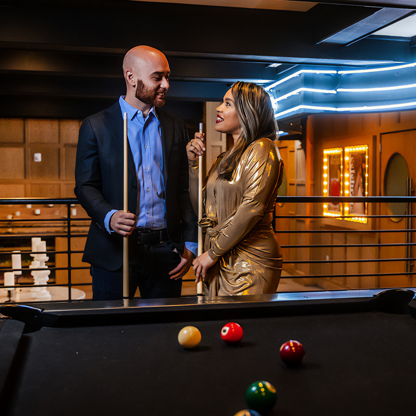 a man and woman standing next to pool table