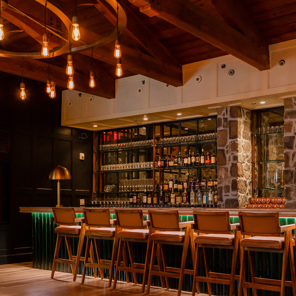 a bar with chairs and a shelf with bottles