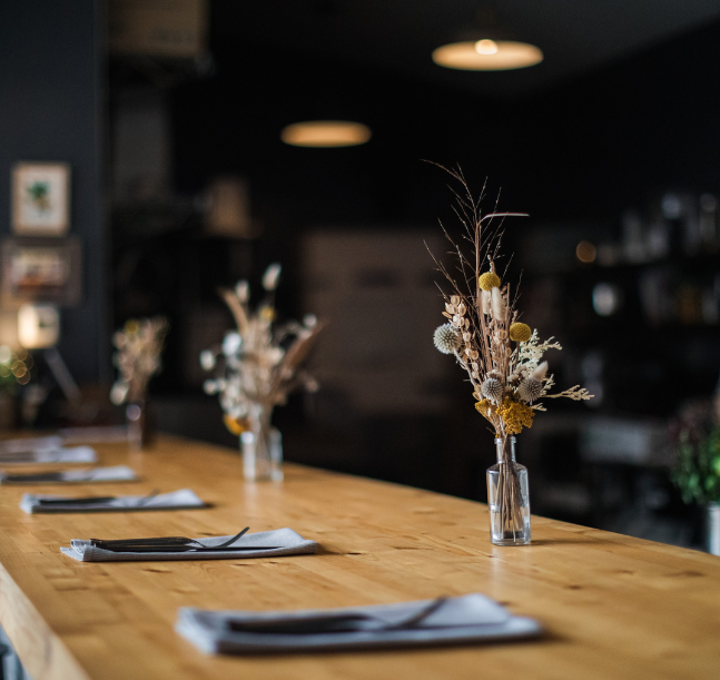 a table with a vase of flowers and cutlery