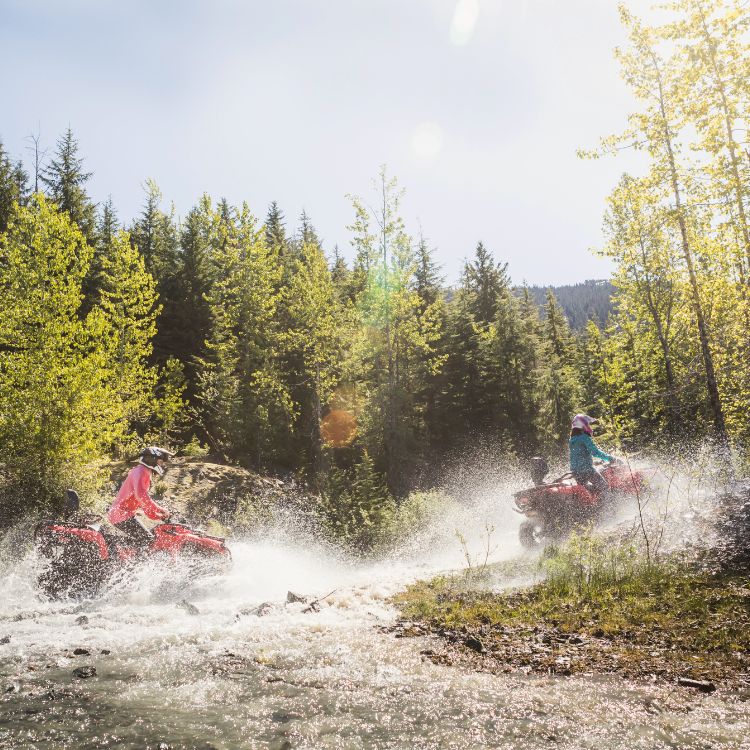two people riding atvs through a river
