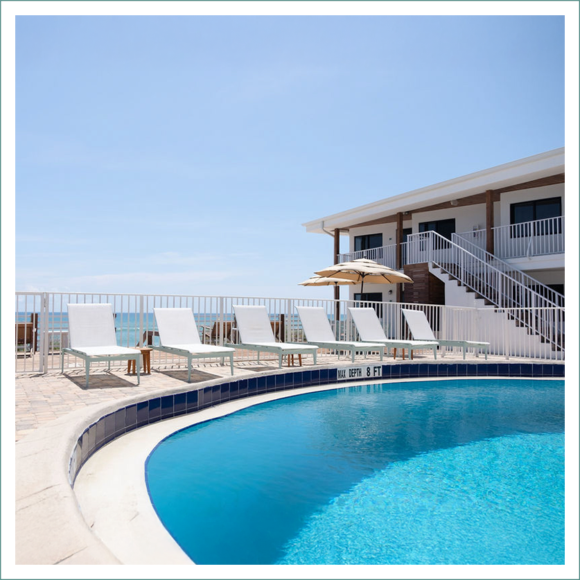 a pool with chairs and umbrellas by a building