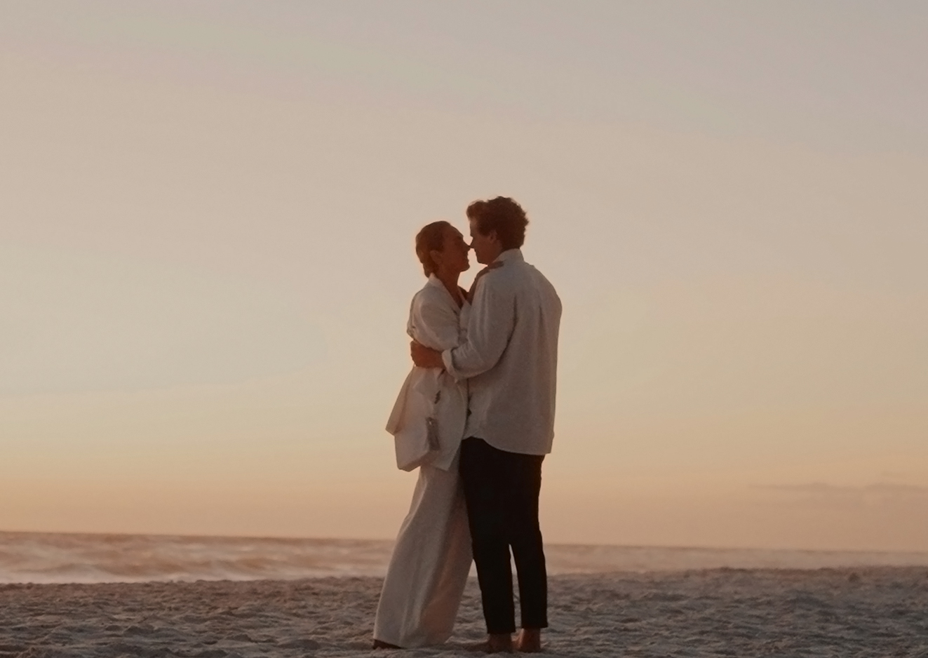 a man and woman kissing on a beach