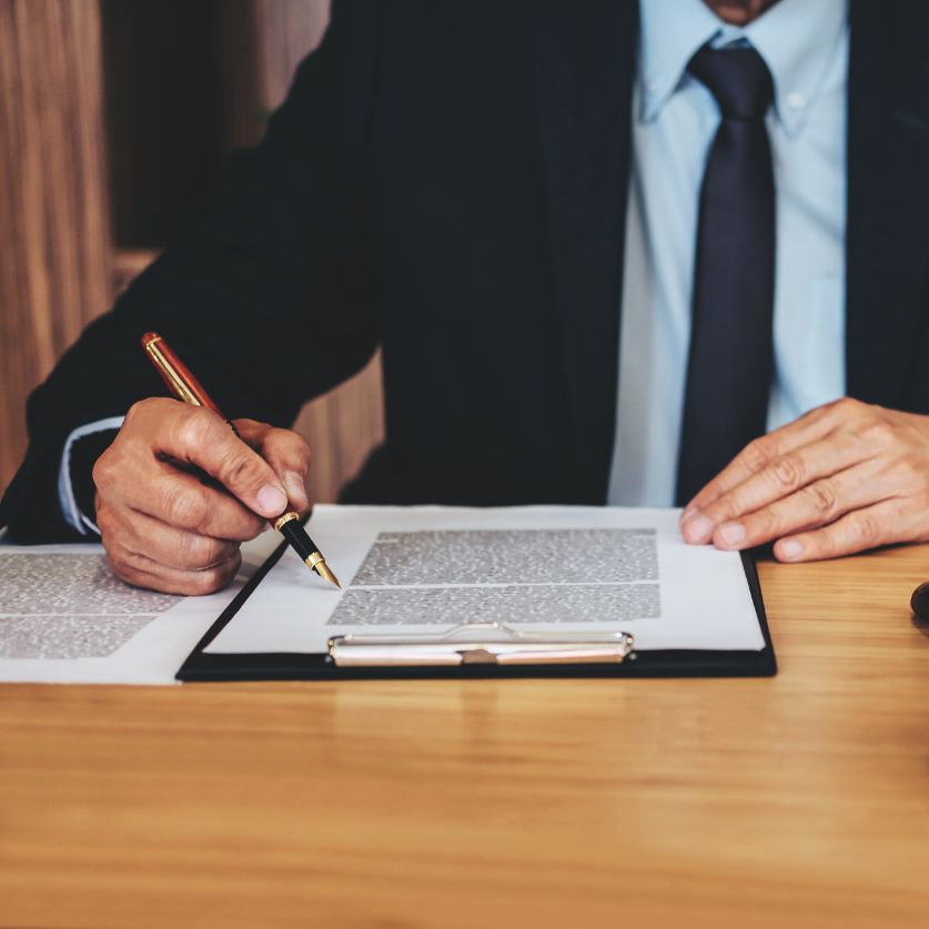 a man in a suit and tie signing a document