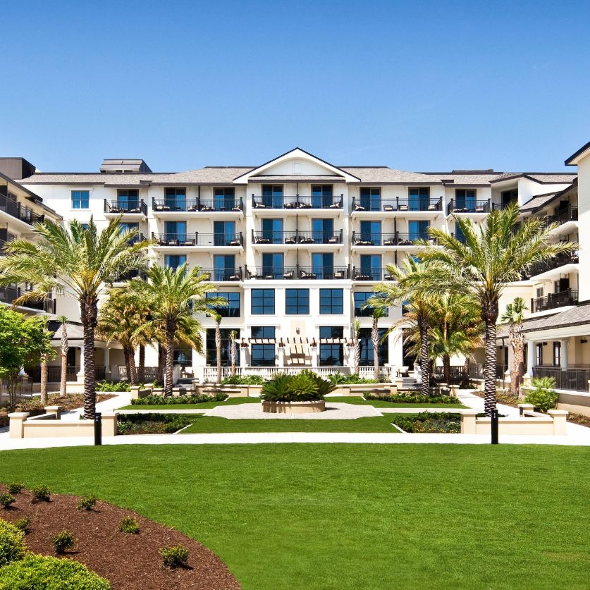 a building with palm trees and a lawn