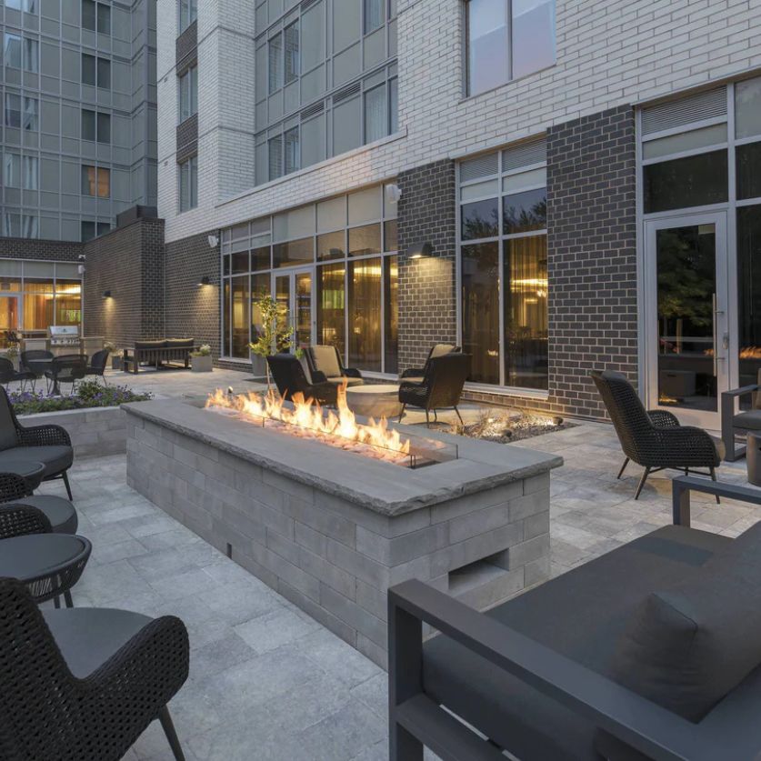 a fire pit with chairs and tables in front of a building