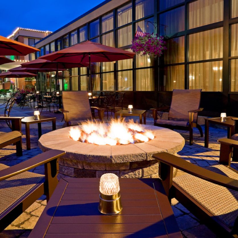 a fire pit with chairs and umbrellas in front of a building