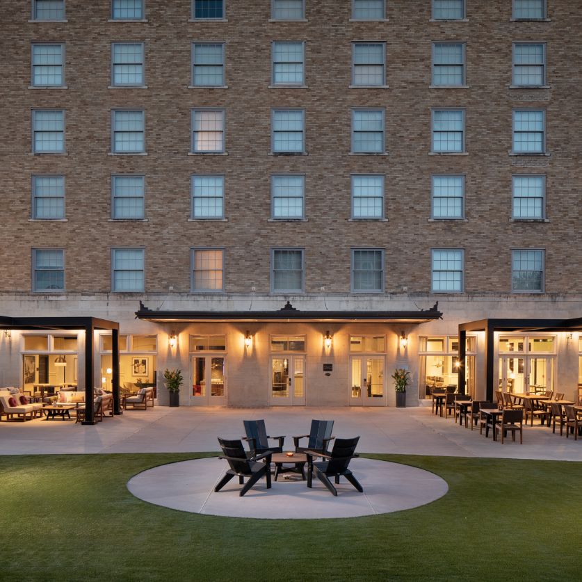 a patio area with chairs and tables in front of a building