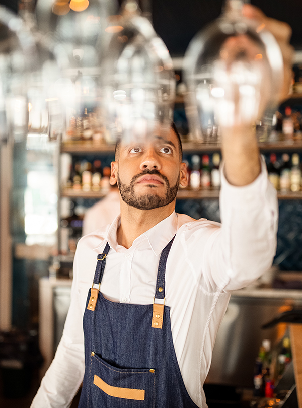 a man in an apron holding up wine glasses