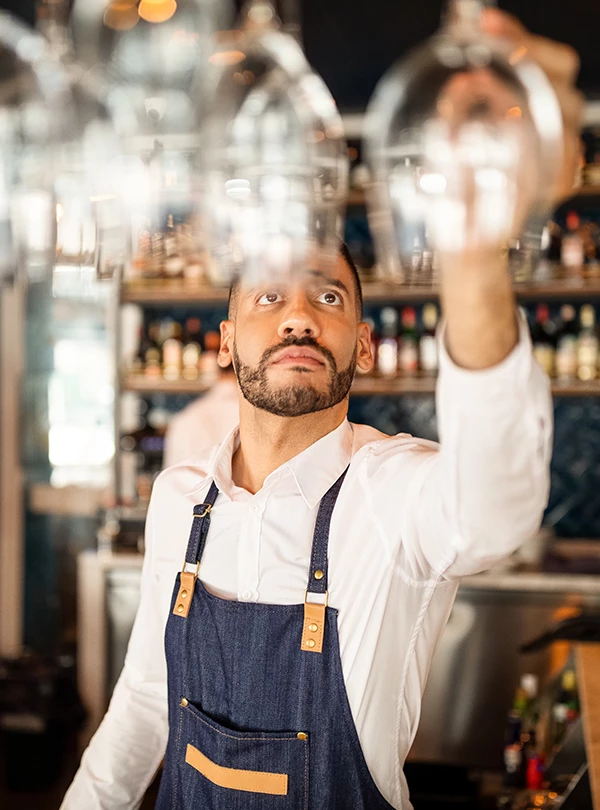 a man in an apron holding up wine glasses