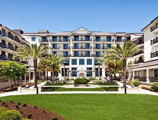 a building with palm trees and a lawn