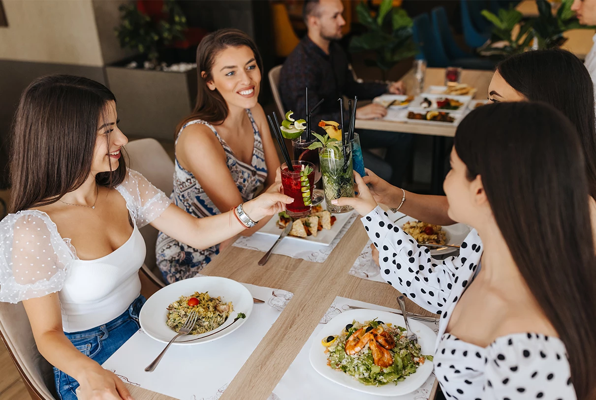 a group of women sitting at a table with food and drinks