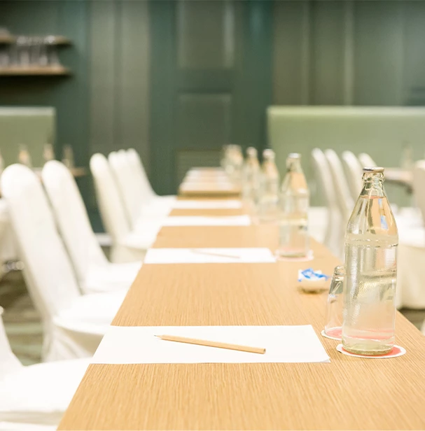 a long table with white chairs and a bottle of water