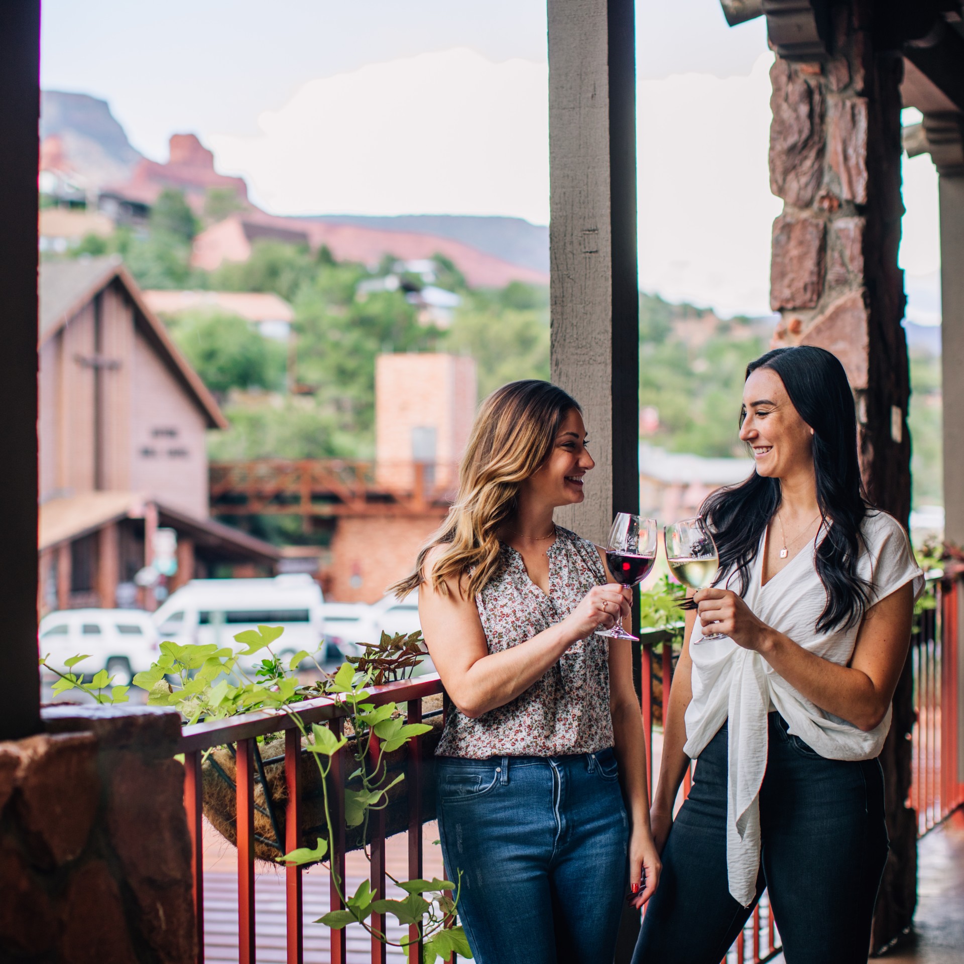 two women holding wine glasses on a porch