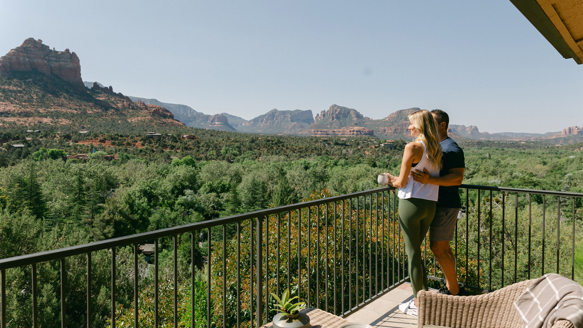 a man and woman standing on a balcony overlooking a valley